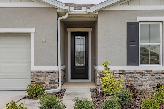 view of exterior entry featuring stone siding, stucco siding, and an attached garage