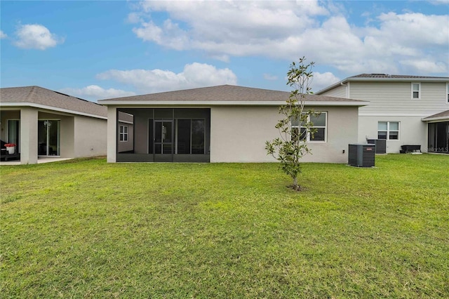 back of property featuring a yard, central AC, stucco siding, and a sunroom