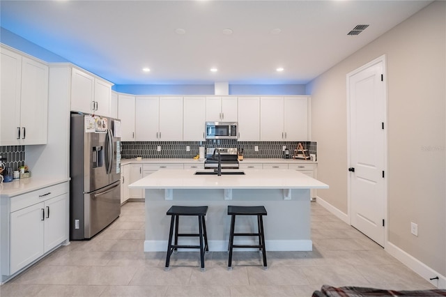 kitchen with visible vents, a breakfast bar, light countertops, appliances with stainless steel finishes, and a sink