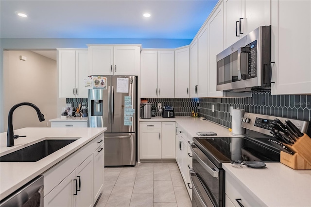 kitchen with a sink, stainless steel appliances, white cabinets, and light countertops