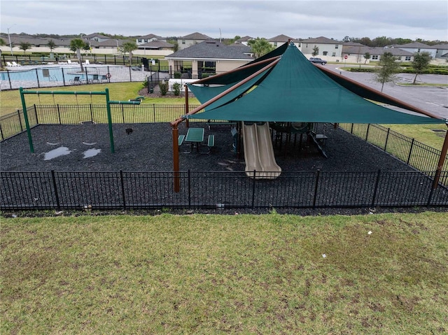 view of property's community with playground community, a yard, and fence