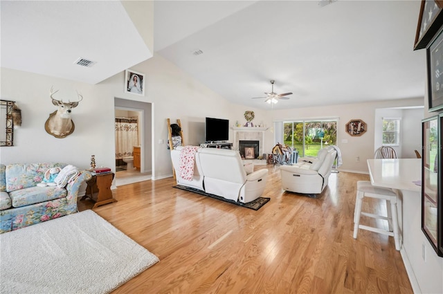 living room featuring visible vents, vaulted ceiling, wood finished floors, and a tile fireplace