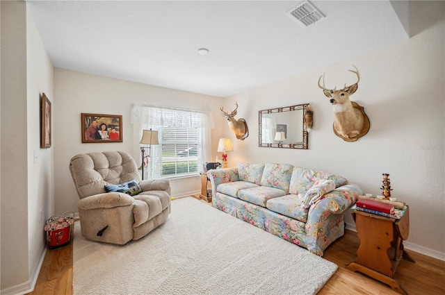 living room featuring wood finished floors, visible vents, and baseboards