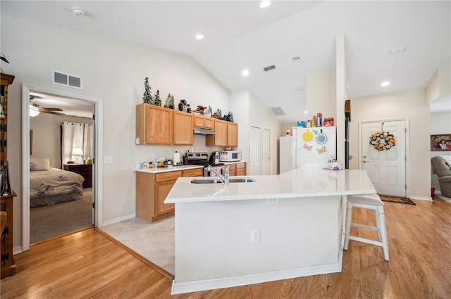 kitchen with white appliances, visible vents, light countertops, under cabinet range hood, and a sink