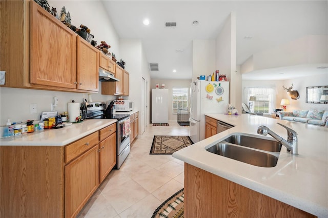 kitchen with stainless steel appliances, a peninsula, a sink, and light countertops