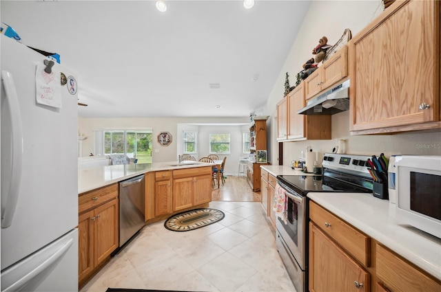 kitchen featuring appliances with stainless steel finishes, a peninsula, light countertops, under cabinet range hood, and light tile patterned flooring