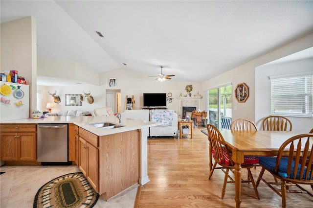 kitchen featuring light countertops, stainless steel dishwasher, open floor plan, a sink, and a peninsula