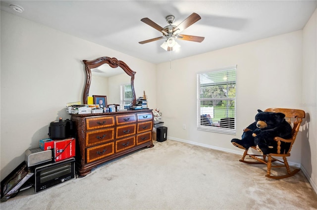 interior space with baseboards, a ceiling fan, and light colored carpet