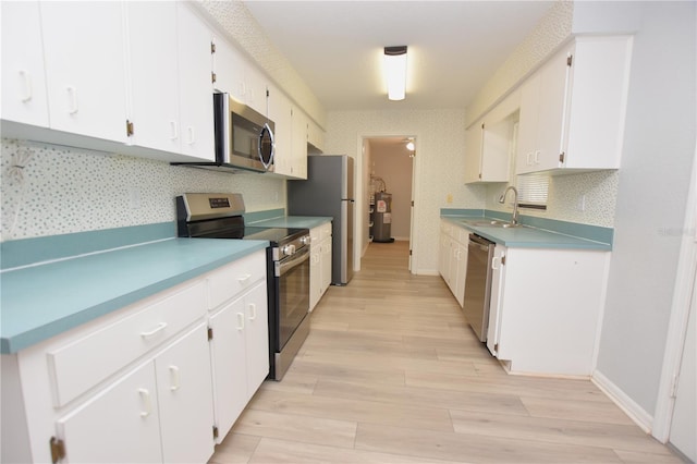 kitchen with light wood-style floors, white cabinetry, stainless steel appliances, and a sink