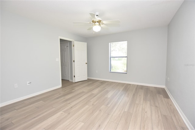 spare room featuring a ceiling fan, baseboards, and light wood finished floors