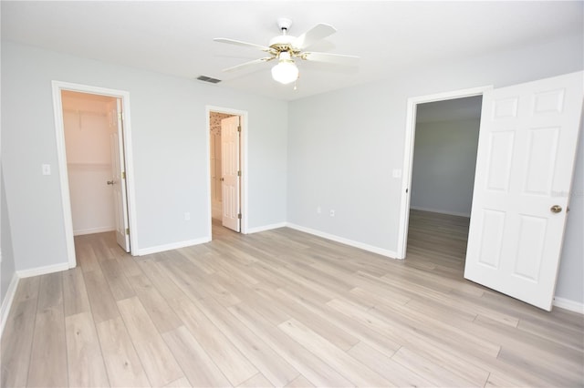 unfurnished bedroom with visible vents, baseboards, light wood-style floors, a spacious closet, and a closet