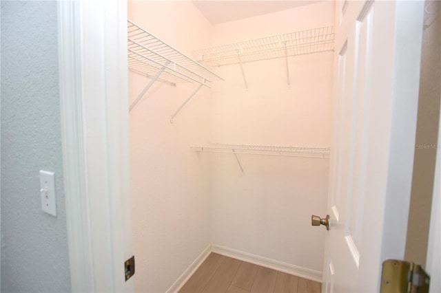 walk in closet with wood finished floors