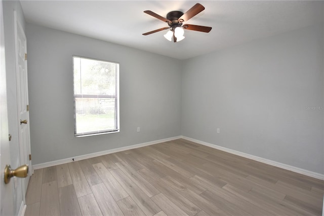 spare room featuring ceiling fan, light wood-style flooring, and baseboards