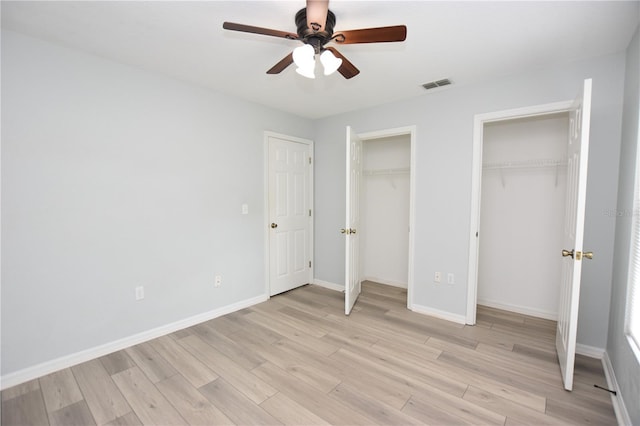 unfurnished bedroom featuring light wood-type flooring, baseboards, visible vents, and multiple closets