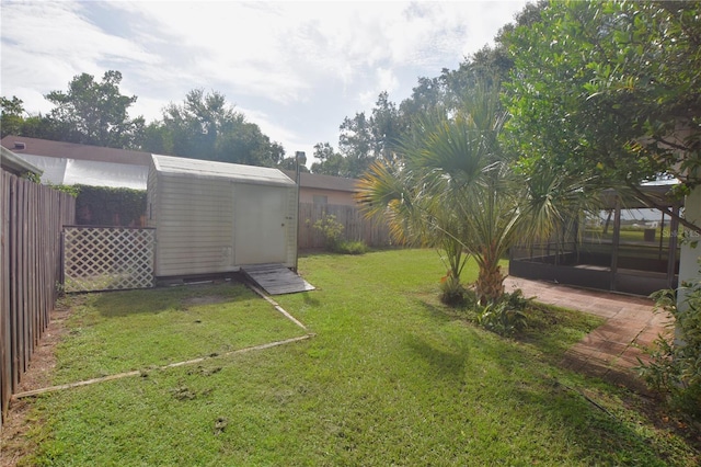 view of yard featuring a storage shed, a fenced backyard, and an outbuilding