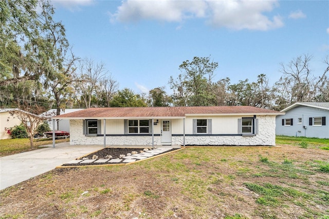 single story home with stone siding, a front lawn, and concrete driveway