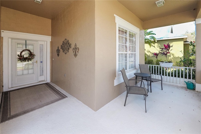 entrance to property featuring covered porch, visible vents, and stucco siding