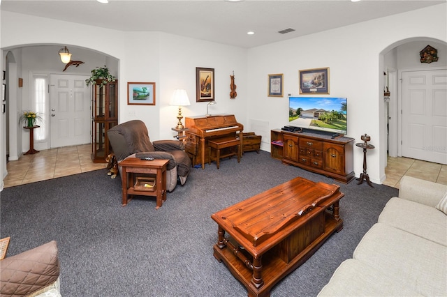 living room with light tile patterned floors, visible vents, and arched walkways