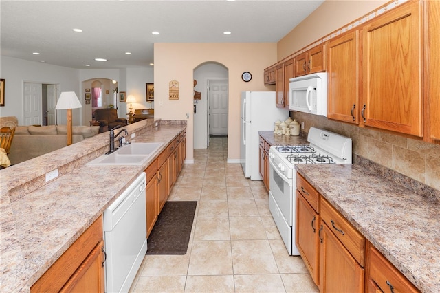 kitchen featuring arched walkways, light tile patterned floors, white appliances, a sink, and open floor plan