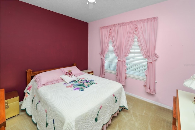 bedroom featuring light carpet, ceiling fan, baseboards, and a textured ceiling