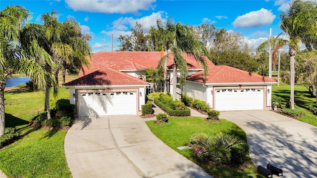 mediterranean / spanish home with a front yard, a tile roof, a detached garage, and stucco siding