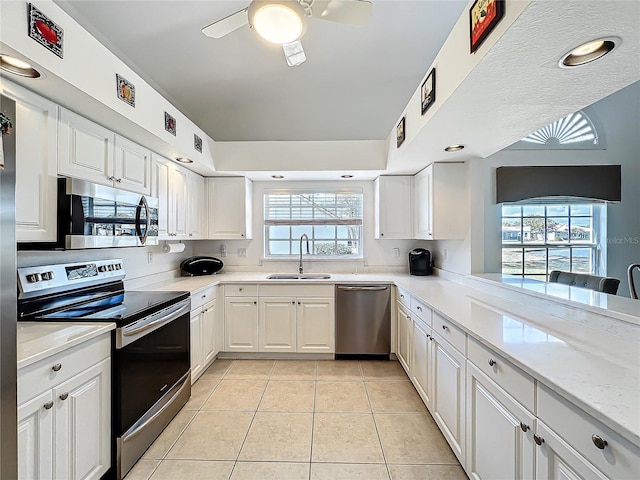 kitchen with ceiling fan, light tile patterned flooring, stainless steel appliances, a sink, and white cabinets