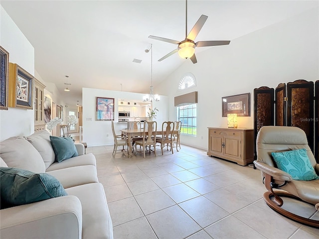 living room with light tile patterned floors, visible vents, high vaulted ceiling, and ceiling fan with notable chandelier