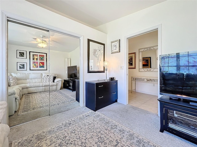 living area with light carpet, ceiling fan, and light tile patterned flooring