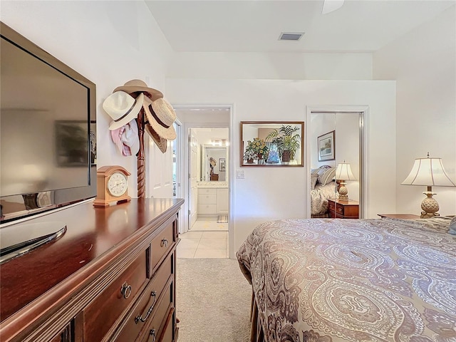 bedroom with visible vents, connected bathroom, light carpet, and light tile patterned floors