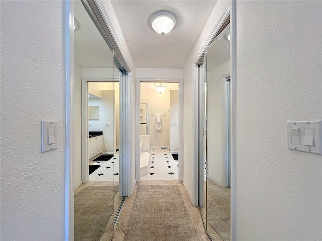 corridor featuring a textured wall and tile patterned flooring