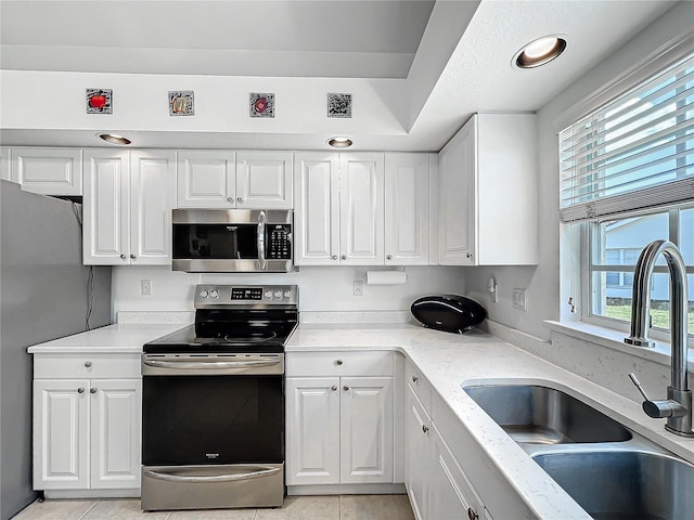 7156 Melrose Pl, Bradenton, FL 34203 - kitchen with stainless steel appliances, a sink, white cabinetry, and light stone countertops