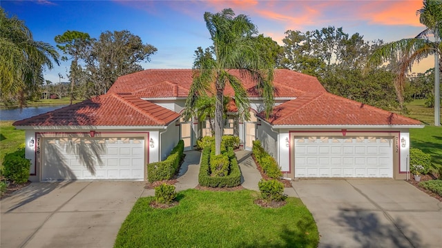 7156 Melrose Pl, Bradenton, FL 34203 - mediterranean / spanish home featuring a tiled roof, concrete driveway, stucco siding, a lawn, and a water view
