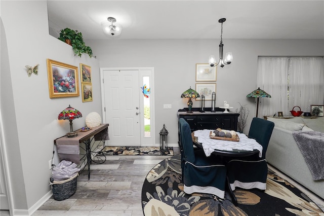 foyer with baseboards, wood finished floors, and an inviting chandelier