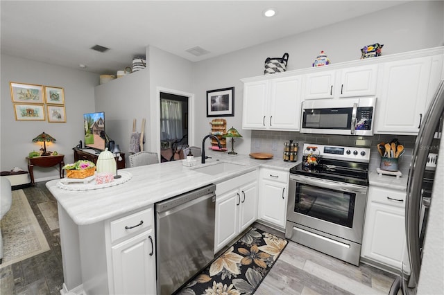 kitchen featuring stainless steel appliances, a peninsula, and white cabinets