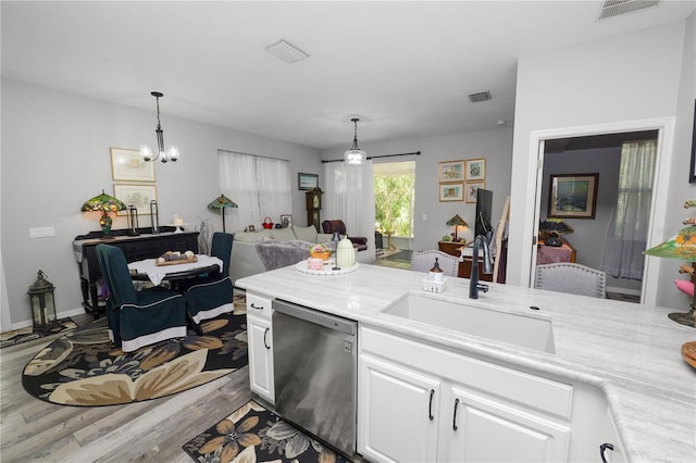 kitchen featuring visible vents, dishwashing machine, light countertops, white cabinetry, and a sink