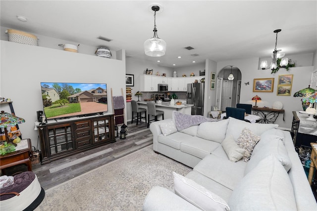 living room featuring visible vents, arched walkways, and wood finished floors