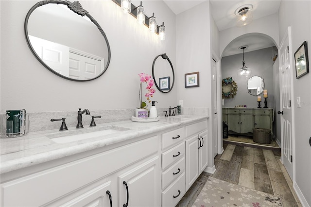 full bath featuring double vanity, wood finished floors, and a sink