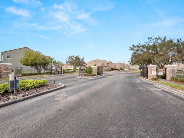 view of street with a residential view, a gate, and curbs