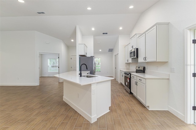 kitchen featuring appliances with stainless steel finishes, wood tiled floor, vaulted ceiling, and a sink