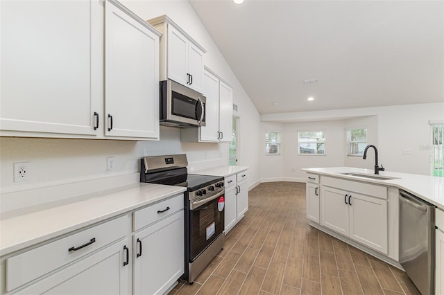 kitchen featuring recessed lighting, wood finished floors, a sink, light countertops, and appliances with stainless steel finishes