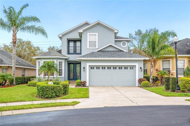 traditional home featuring driveway, a shingled roof, stucco siding, french doors, and a front yard