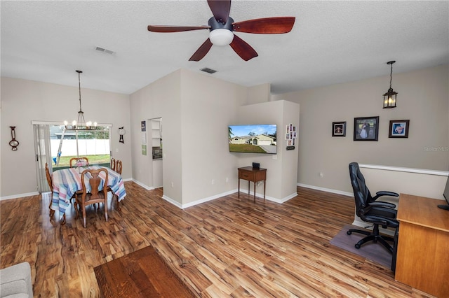 dining room featuring a textured ceiling, wood finished floors, visible vents, and baseboards