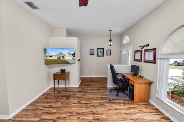 office space featuring a wealth of natural light, wood finished floors, visible vents, and baseboards