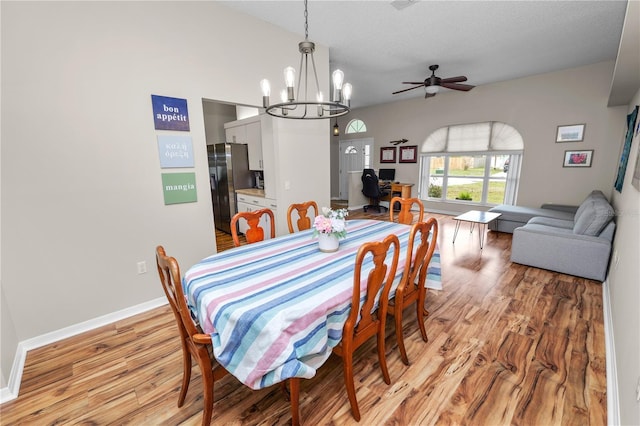 dining room with ceiling fan with notable chandelier, light wood-style flooring, baseboards, and a textured ceiling