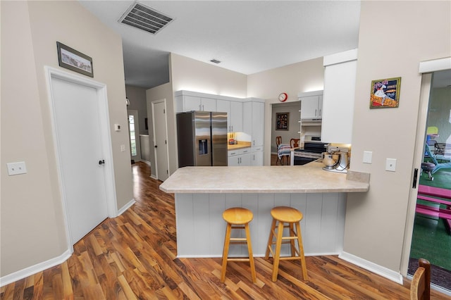 kitchen with a breakfast bar area, a peninsula, visible vents, light countertops, and appliances with stainless steel finishes