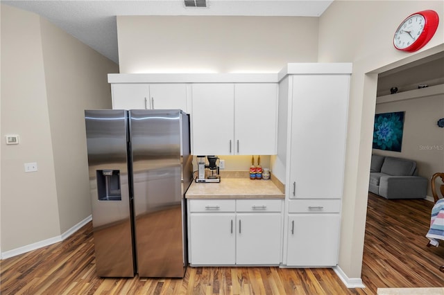 kitchen featuring stainless steel fridge, visible vents, white cabinets, light countertops, and light wood-type flooring