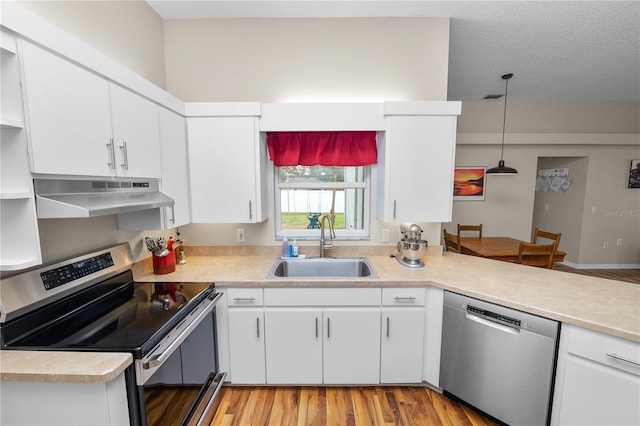 kitchen featuring under cabinet range hood, a sink, white cabinetry, light countertops, and appliances with stainless steel finishes