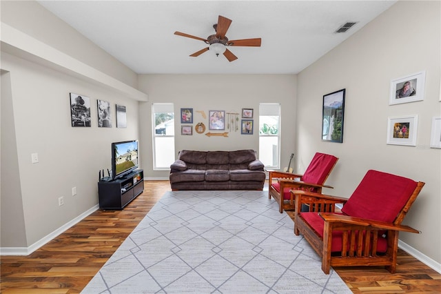 living area with baseboards, ceiling fan, visible vents, and wood finished floors