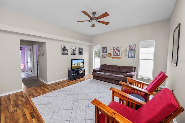 living area featuring ceiling fan, a textured ceiling, wood finished floors, and baseboards