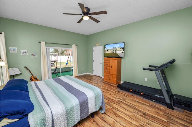 bedroom with a textured ceiling, wood finished floors, a ceiling fan, baseboards, and access to outside